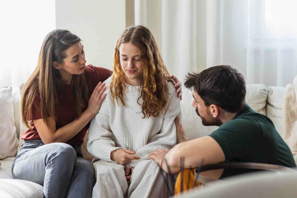 Parents comforting their teen while discussing treatment options at home