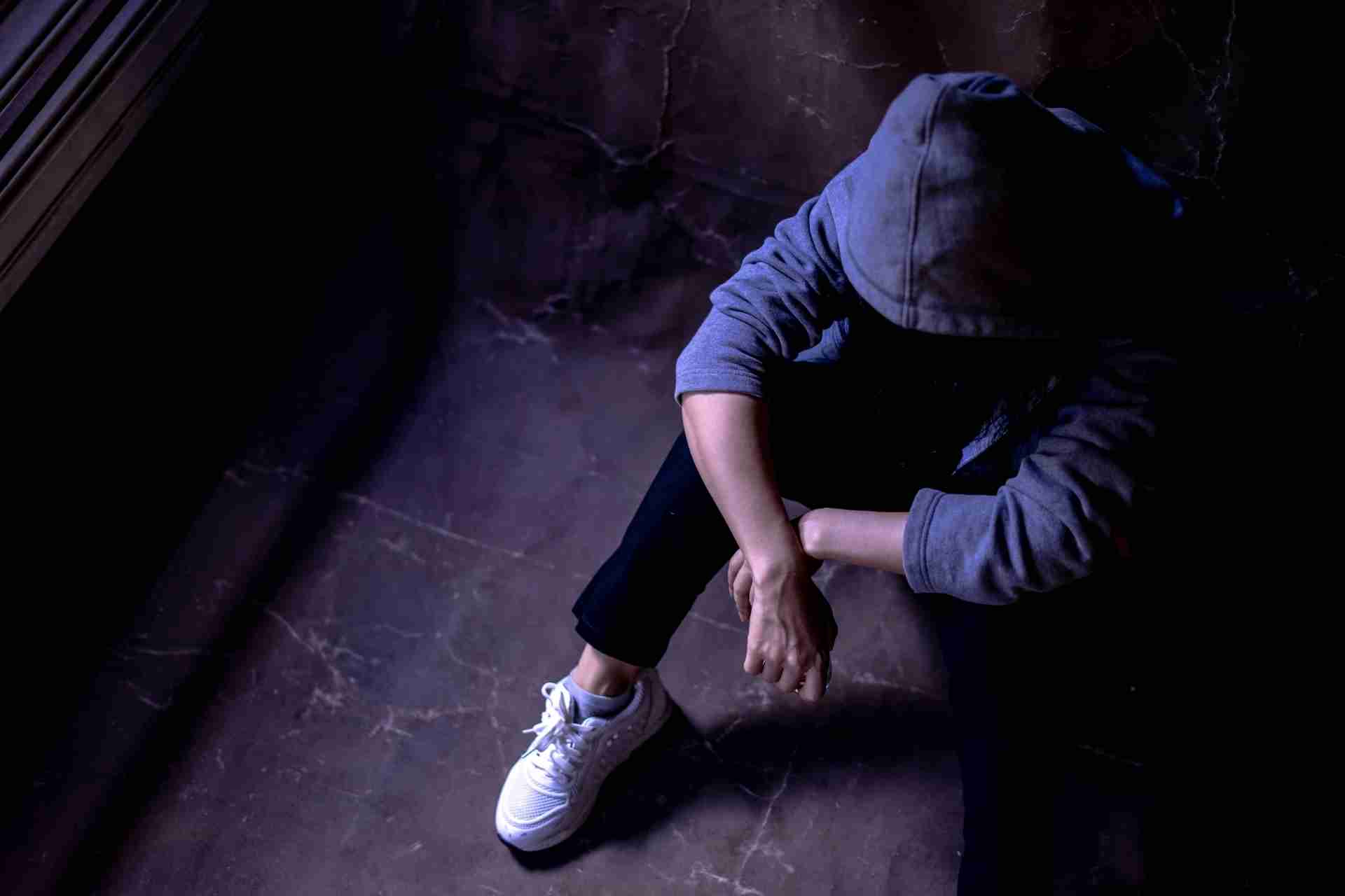 Person sitting alone reflecting on substance use patterns and recovery challenges