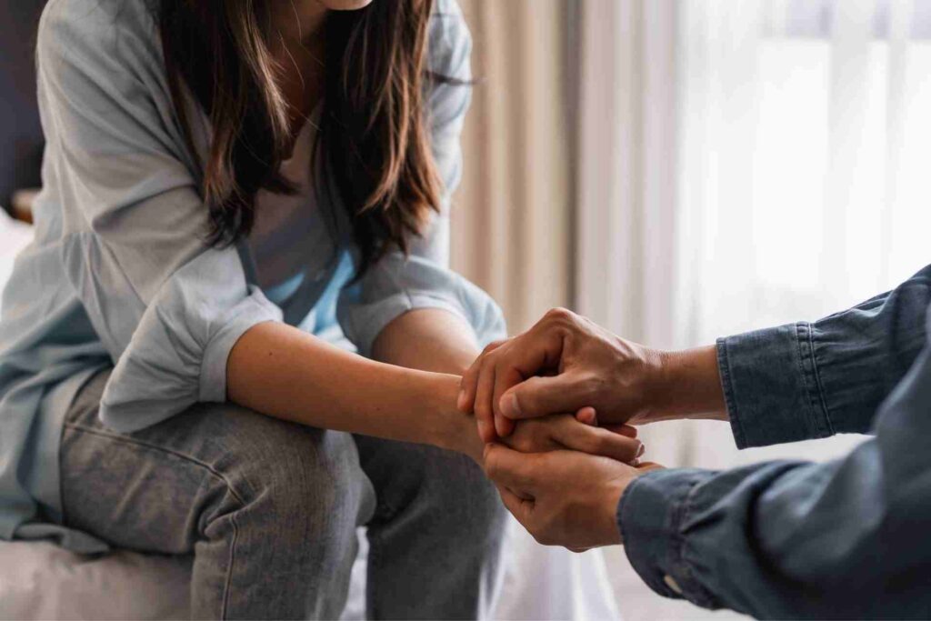 A loved one holds someone's hands to provide comfort and support during addiction recovery.