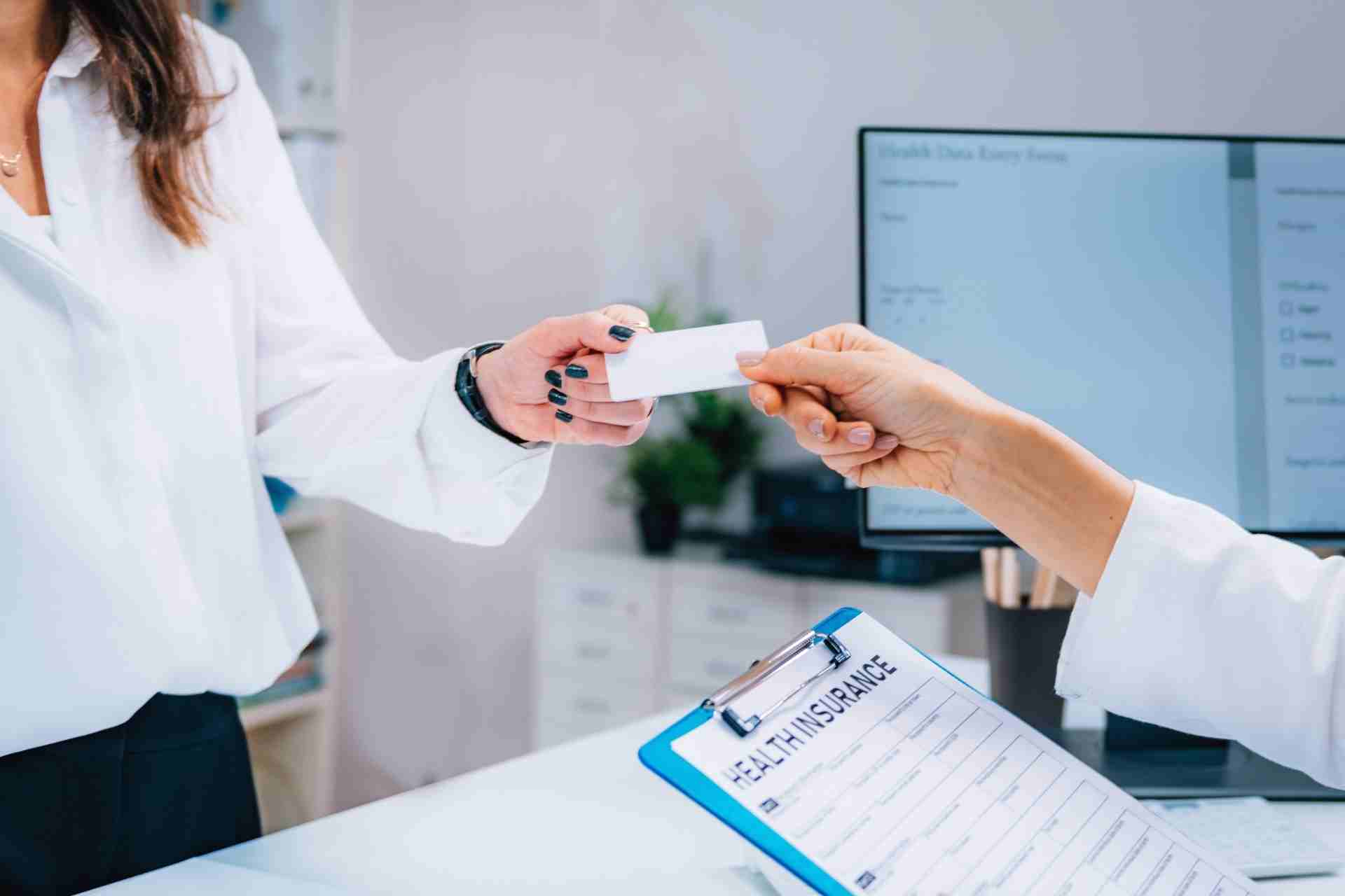 Patient handing an insurance card to verify coverage for addiction treatment.