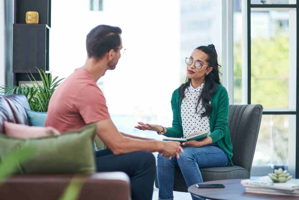 Therapist speaking with a client during an initial dual-diagnosis treatment consultation in a comfortable outpatient counseling office.