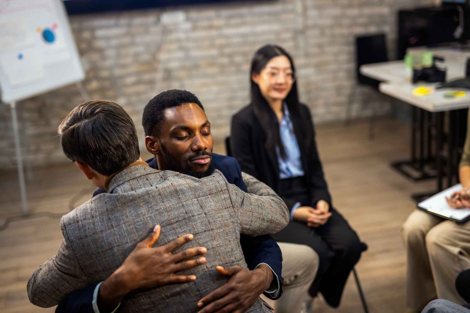 Two people embracing during an aftercare peer support group