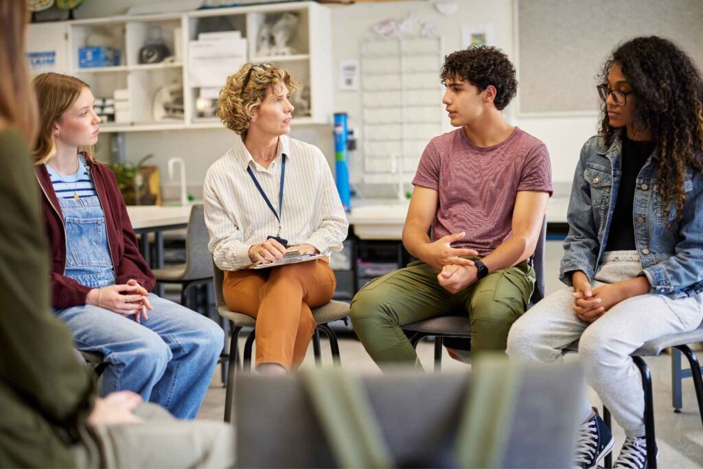 Young adults speaking with a counselor during a recovery support group.