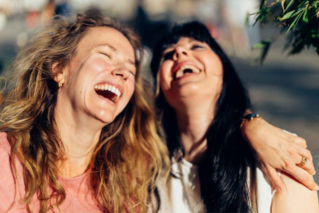 Adult women laughing during group therapy for PTSD and addiction dual diagnosis treatment.